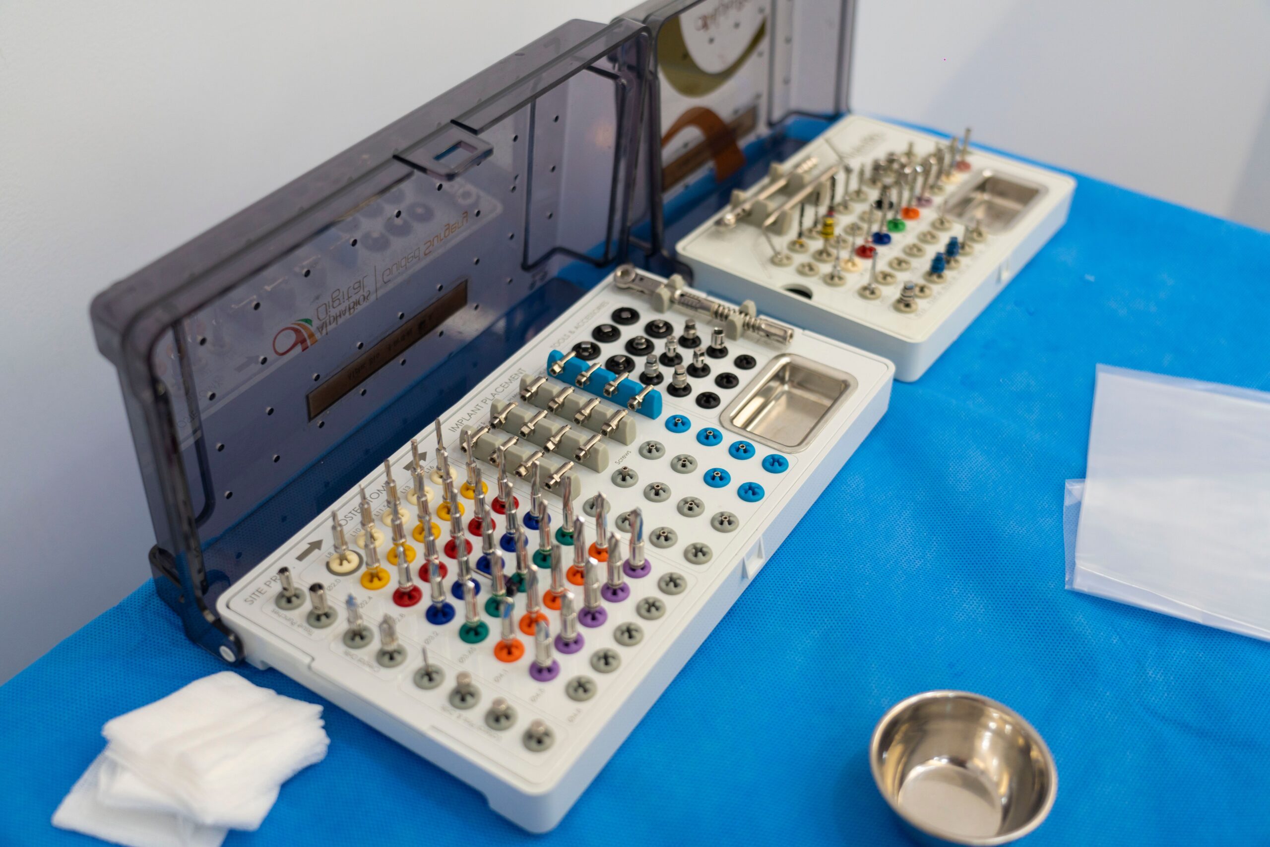Close-up of a dental implant drill kit on a table with colorful bits arranged in rows.